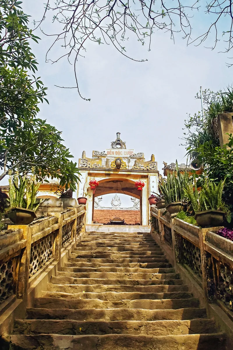 Bậc thang đá dẫn lên cổng đền Độc Cước với cây cảnh trồng trong chậu hai bên.